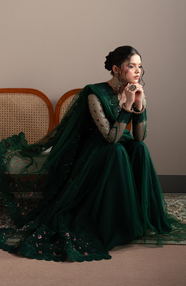 Woman in a green dress sitting on a chair with a neutral background