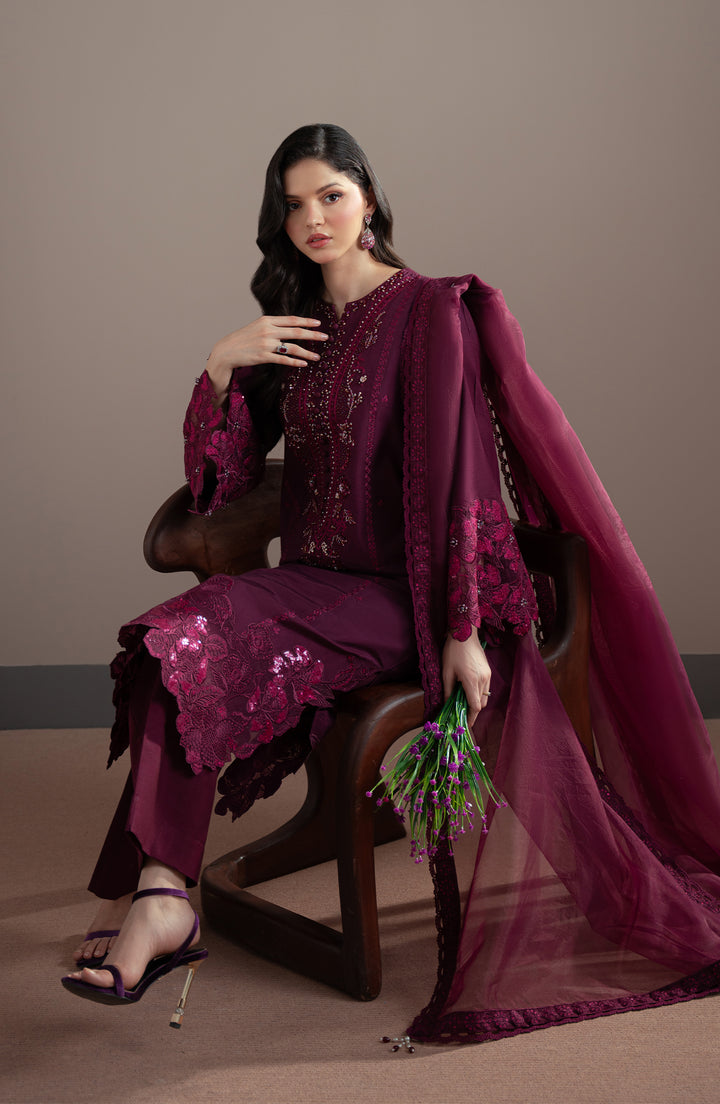Woman in a purple traditional outfit sitting on a chair against a plain background