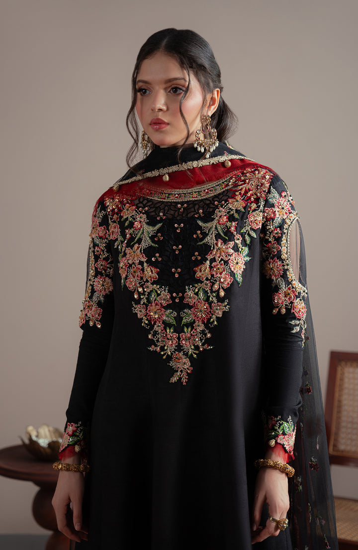 Woman wearing a black outfit with floral embroidery in a room setting