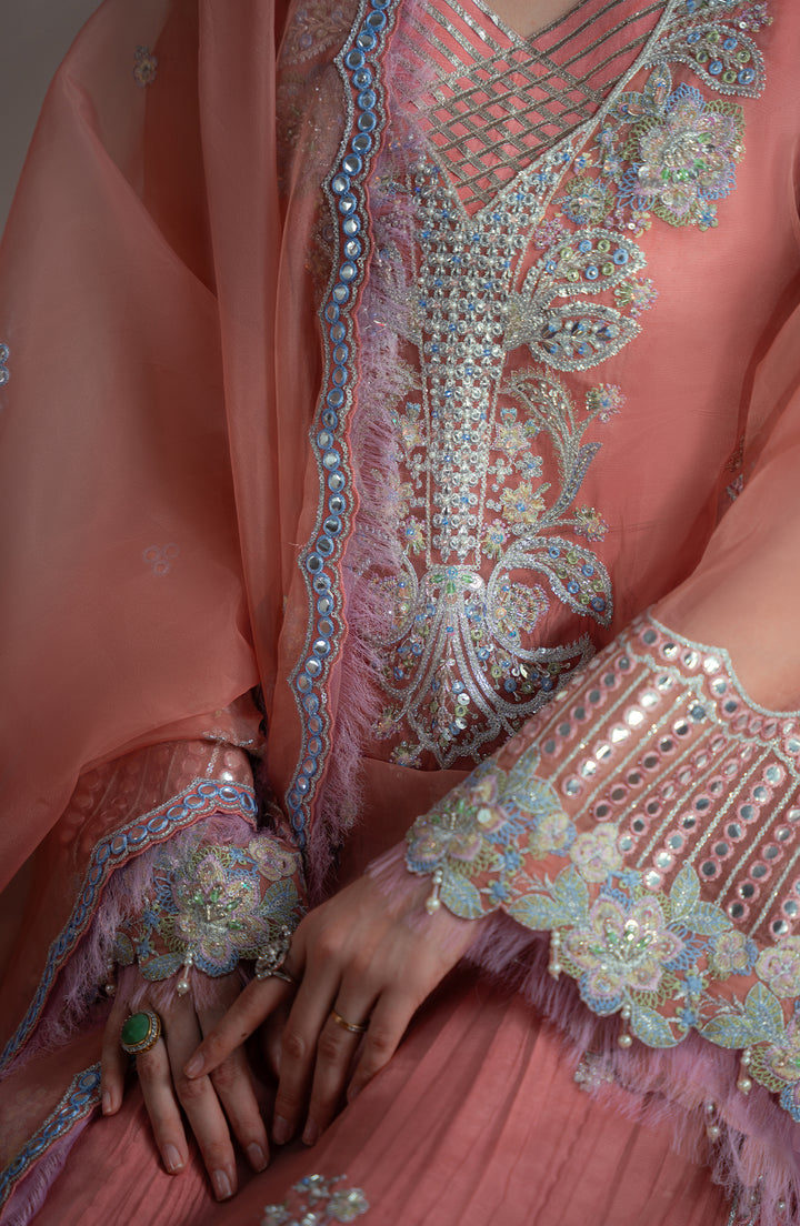 Close-up of a pink embroidered traditional outfit with intricate patterns.